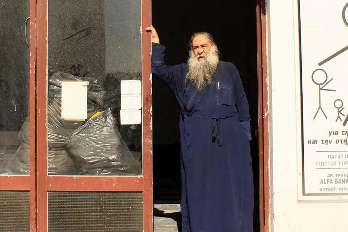 Отец Стратис Диму, грчки православен свештеник на островот Лезбос, во добротворната организација што ја основа за да им помогне на бегалците и емигрантите. Фото: Костас Кукумакас