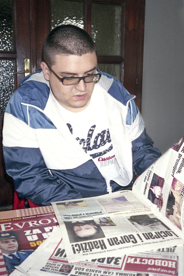 Среќко,син на хашкиот обвинет Горан Хаџиќ, ги разгледува новинските написи од времетокога неговиот татко бил бегалец