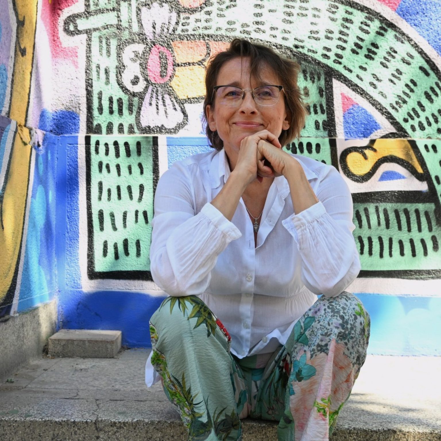 Фотографија од актерката Синоличка Трпкова пред муралот „Бушава азбука“ во Дебар Маало.